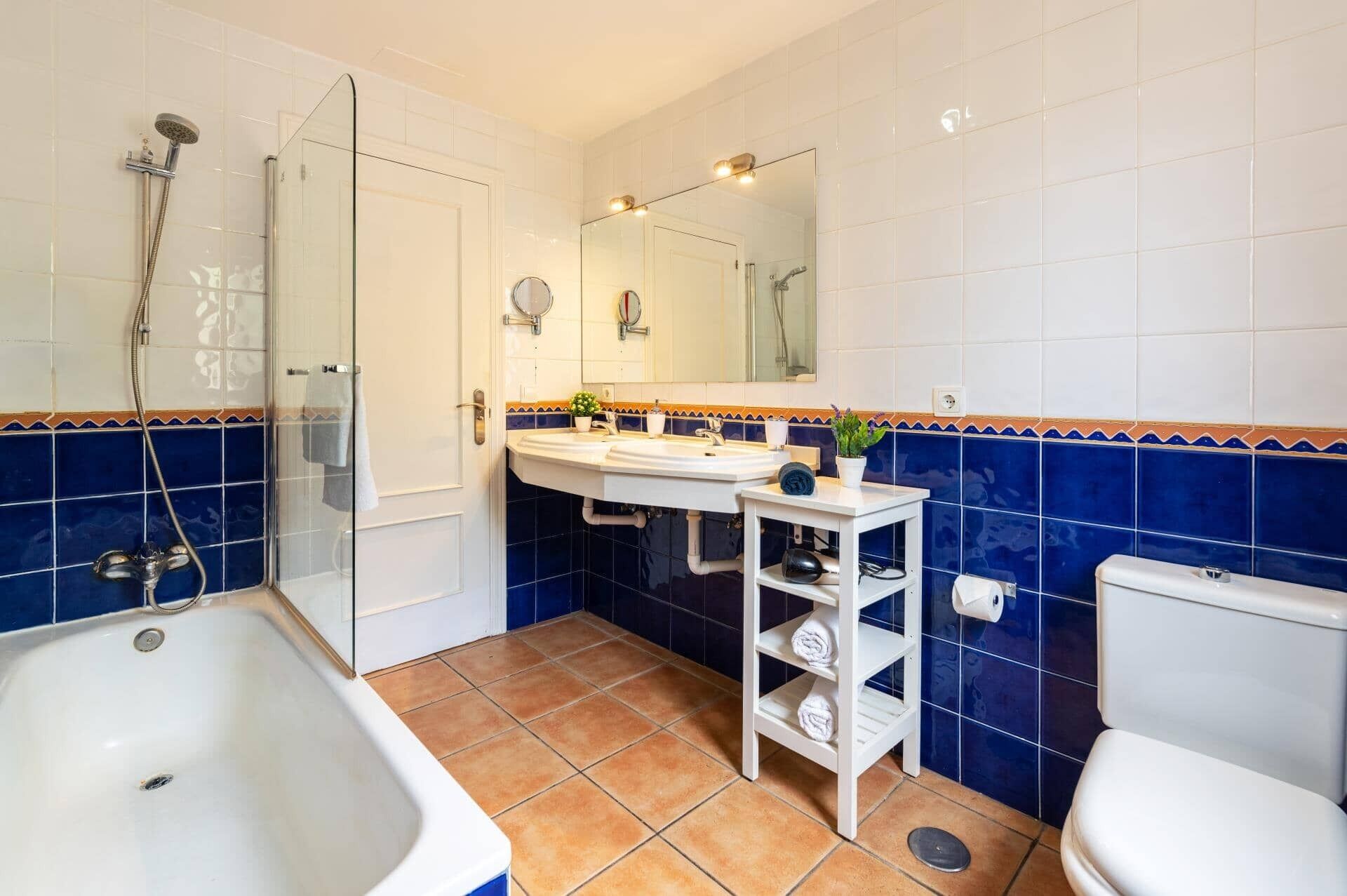 A bathroom with a glass-enclosed shower, a white sink with a mirror above it, and a toilet.
