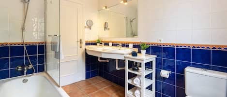 A bathroom with a glass-enclosed shower, a white sink with a mirror above it, and a toilet.