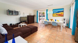 A living room with a sofa, TV, and a dining area with a table and chairs.