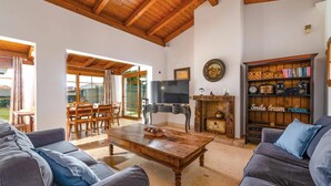 A spacious living room with a wooden ceiling, a fireplace, a television, and a bookshelf. - Villa Sherry by Villa Plus (Corralejo)