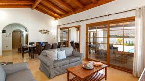 Amplia sala de estar con un sofá gris, una mesa de centro de madera y una zona de comedor con sillas y una mesa.