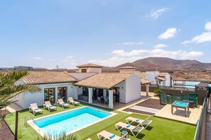 A resort with a swimming pool, lounge chairs, and a view of mountains.