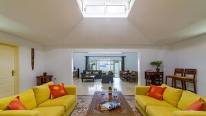 A spacious living room with yellow sofas, a patterned coffee table, and a view into the dining area. - Villa Esmeralda by Villa Plus (Corralejo)