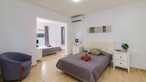 A bedroom with a large bed, two bedside tables, a chair, and a window with curtains. - Villa Esmeralda by Villa Plus (Corralejo)