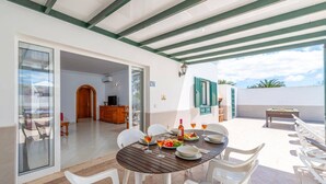 Un patio cubierto con una mesa de comedor para cuatro, una mesa de billar y vistas al mar.