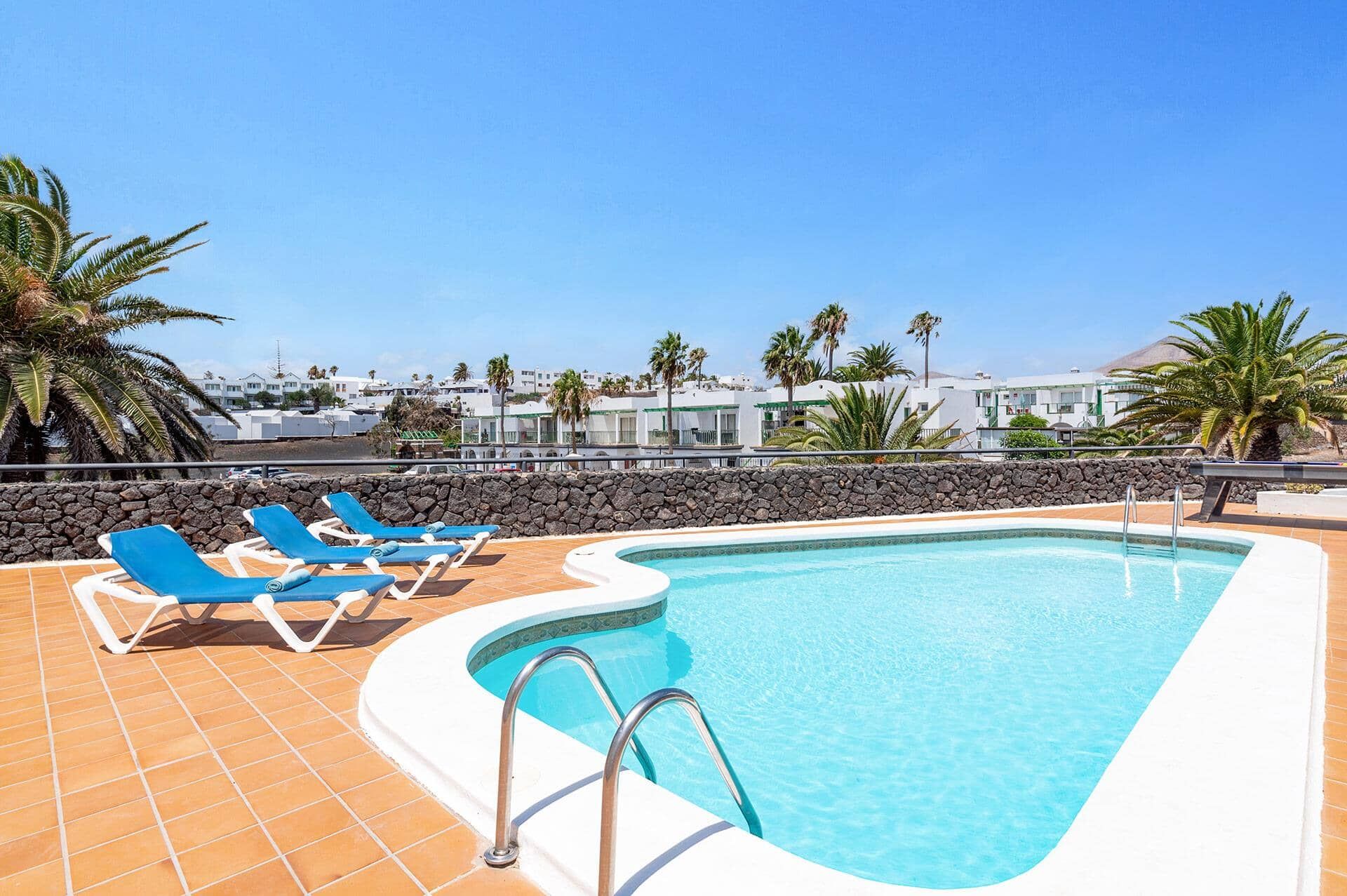 A swimming pool with a stone wall and a clear blue sky.