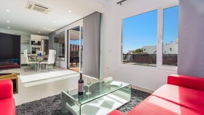 A modern living room with a glass coffee table, red sofa, and a view of the sky through large windows. - Villa Kikay by Villa Plus (Tías)