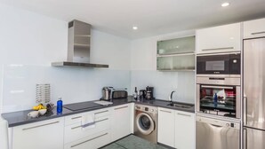 A modern kitchen with a washing machine, Bosch appliances, and a stainless steel refrigerator. - Villa Kikay by Villa Plus (Tías)