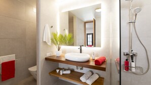 A modern bathroom with a large mirror, white sink, and a shower with a handheld showerhead. - Villa JJ Beach by Villa Plus (Tías)