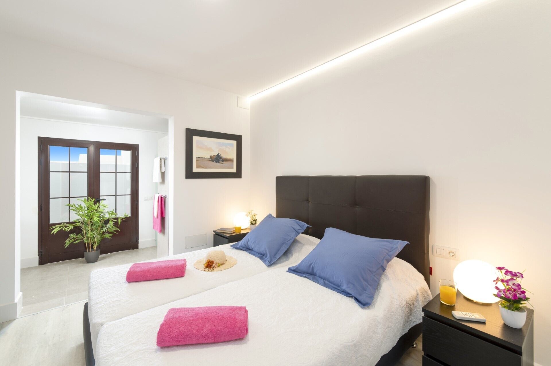 Une chambre d’hôtel avec un lit, une table de chevet et une porte donnant sur le couloir.