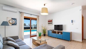 A modern living room with a sofa, TV, and a glass coffee table.