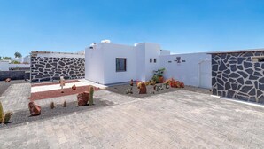 A rooftop with white walls, a stone wall, and potted plants.