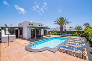 Une maison moderne dotée d’une piscine, d’un espace salon extérieur et d’un jardin.