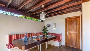 Een eetruimte met een houten tafel, een bank met strepen en een houten deur.