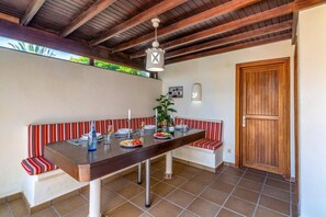 Een eetruimte met een houten tafel, een bank met strepen en een houten deur.