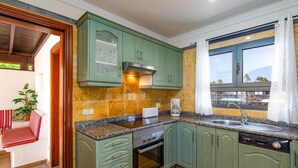Een keuken met groene kastjes, een ingebouwde oven, een koffiezetapparaat en een raam met uitzicht.