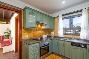 Een keuken met groene kastjes, een ingebouwde oven, een koffiezetapparaat en een raam met uitzicht.