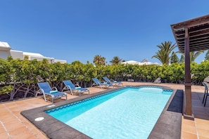 A swimming pool with lounge chairs and a clear blue sky.