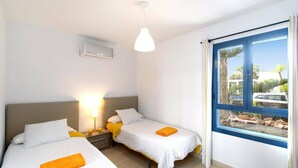 Une chambre d’hôtel avec deux lits, une table de chevet avec une lampe et une fenêtre donnant sur l’extérieur.
