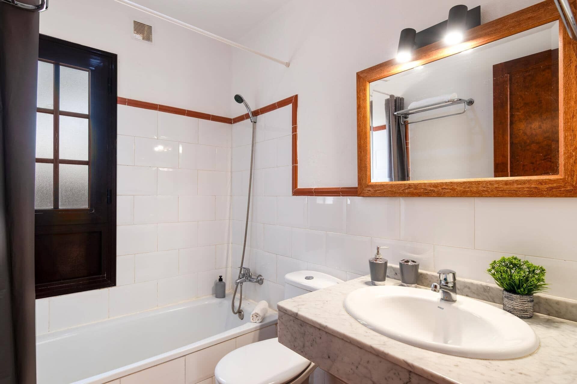 A bathroom with a bathtub, toilet, sink, and mirror.