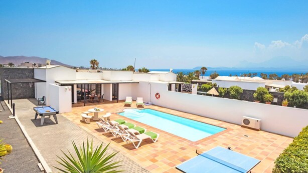 Area piscina sul tetto con poltrona a sdraio, tavolo da biliardo e vista sul mare.