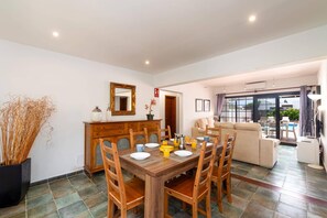 Un coin repas avec une table en bois dressée pour quatre personnes, entourée de chaises en bois.