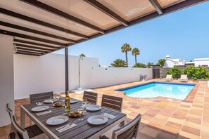 An outdoor dining area with a pool, covered patio, and a view of the surrounding landscape. - Villa Yeray by Villa Plus (Playa Blanca)