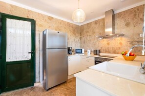 A modern kitchen with a stainless steel refrigerator, a coffee maker, a microwave, and a sink with a fruit bowl.