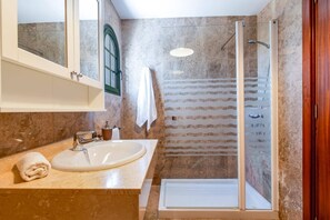Une salle de bain équipée d’un lavabo, d’un miroir, d’une serviette et d’une douche.