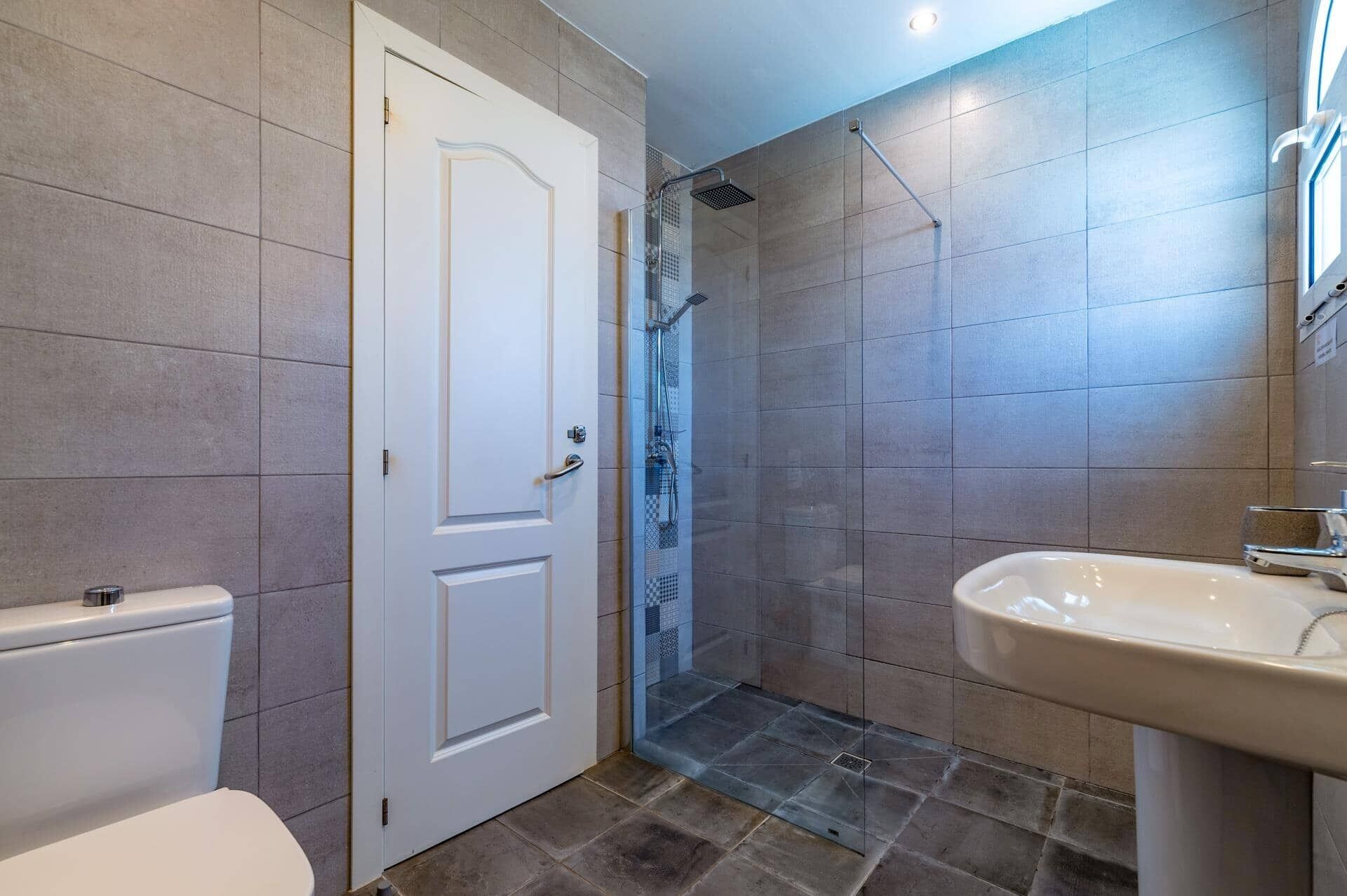 A bathroom with a toilet, a shower with a glass door, and a sink.