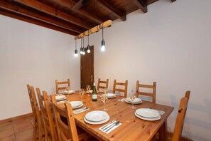 A dining area with a wooden table set for four, surrounded by wooden chairs.