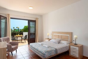 Una camera da letto con un letto, comodini, una sedia e un balcone con tavolo e sedie.