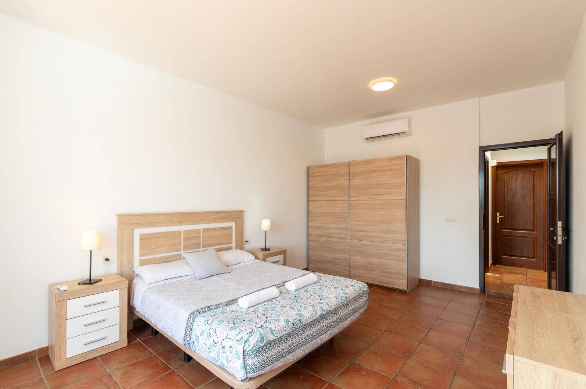 Une chambre à coucher avec un lit, des tables de chevet, une armoire et une porte.