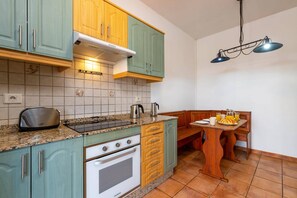 Una cocina con estufa, hervidor y preparación para desayuno sobre la mesa.