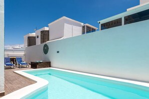 Una piscina con un muro blanco y un cielo azul despejado.