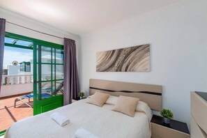 Habitación de hotel con cama, vista al exterior, un cuadro en la pared y una ventana con cortinas.