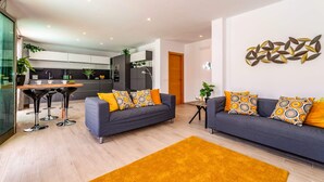 Ein modernes Wohnzimmer mit zwei grauen Sofas, einem Holztisch und einem gelben Teppich.