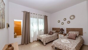 Ein Hotelzimmer mit zwei Betten, einem Holzkopfstück, einem Nachttisch, einer Lampe und dekorativen Wandleuchten.