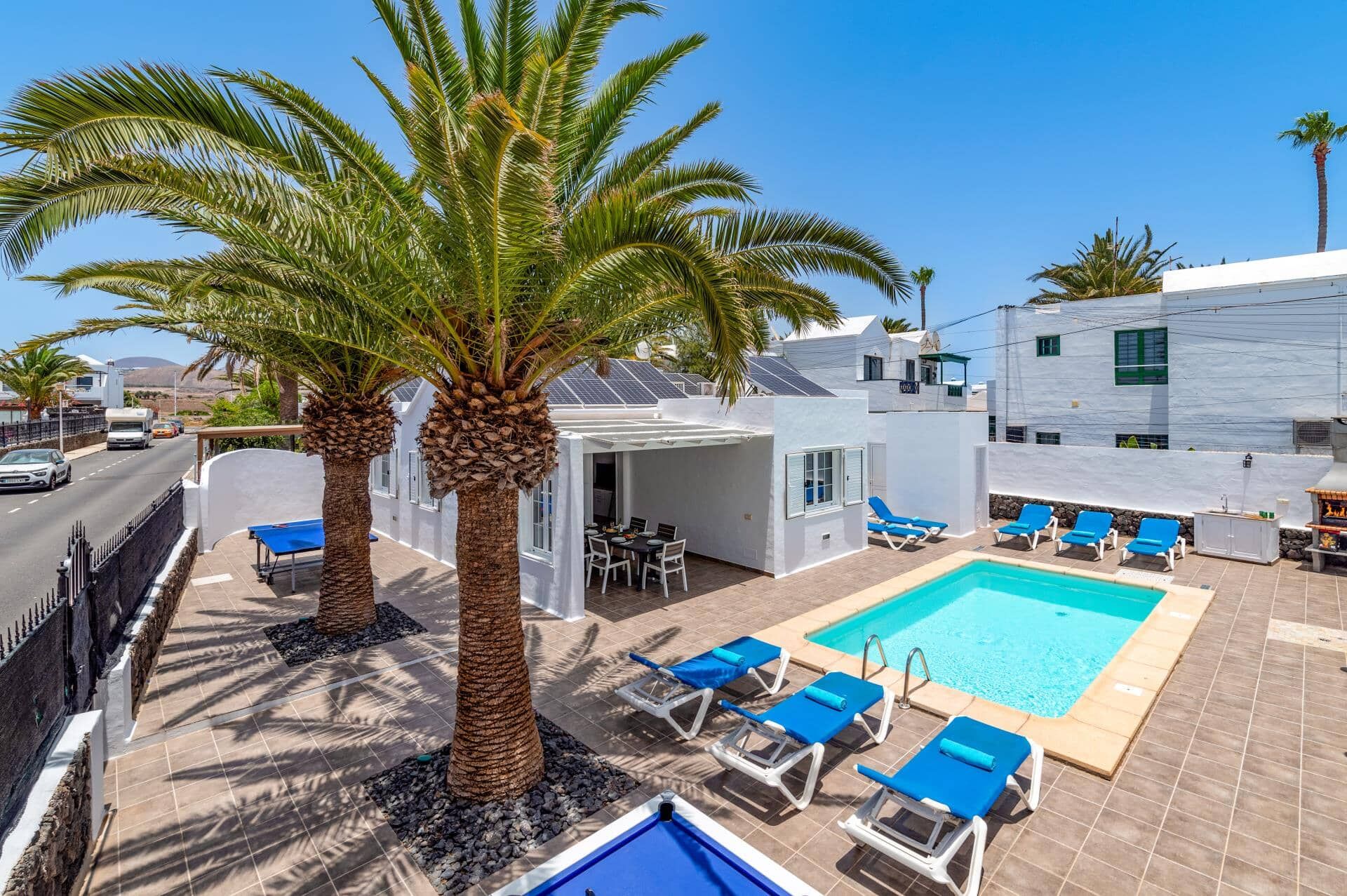 A poolside area with lounge chairs, a pool, and a building with solar panels.