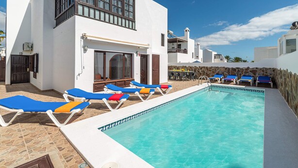 Zona de piscina con sillas de descanso y un muro de piedra.