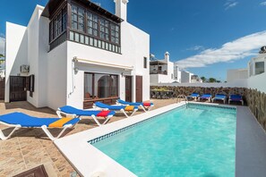 A pool area with lounge chairs and a stone wall.