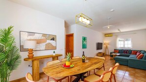 A spacious living area with a wooden dining table surrounded by wicker chairs, a green sofa, and a large potted plant. - Villa Laurona by Villa Plus (Puerto del Carmen)