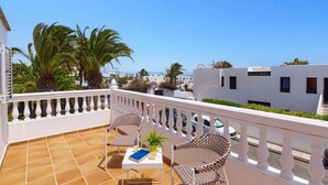 A terrace with two wicker chairs, a small table with a book and a plant, and a white railing. - Villa Laurona by Villa Plus (Puerto del Carmen)