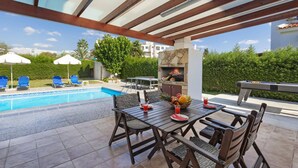 Un espace extérieur avec piscine, barbecue, coin salon et vue sur la piscine.