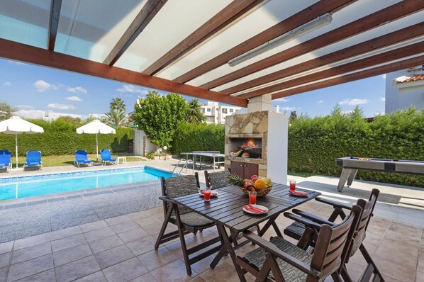 An outdoor pool area with a barbecue grill, seating, and a view of the pool.