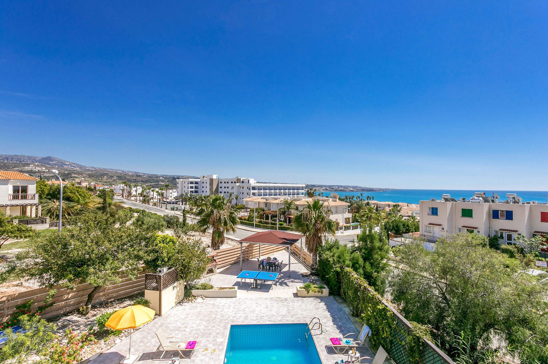 A residential area with a swimming pool, outdoor seating, and a view of the sea.