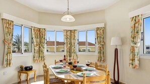Comedor con una mesa redonda dispuesta para cuatro personas, rodeado de sillas de madera con asientos de mimbre.