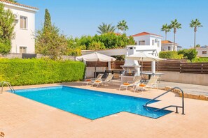 Una piscina con lettini e un'area barbecue.