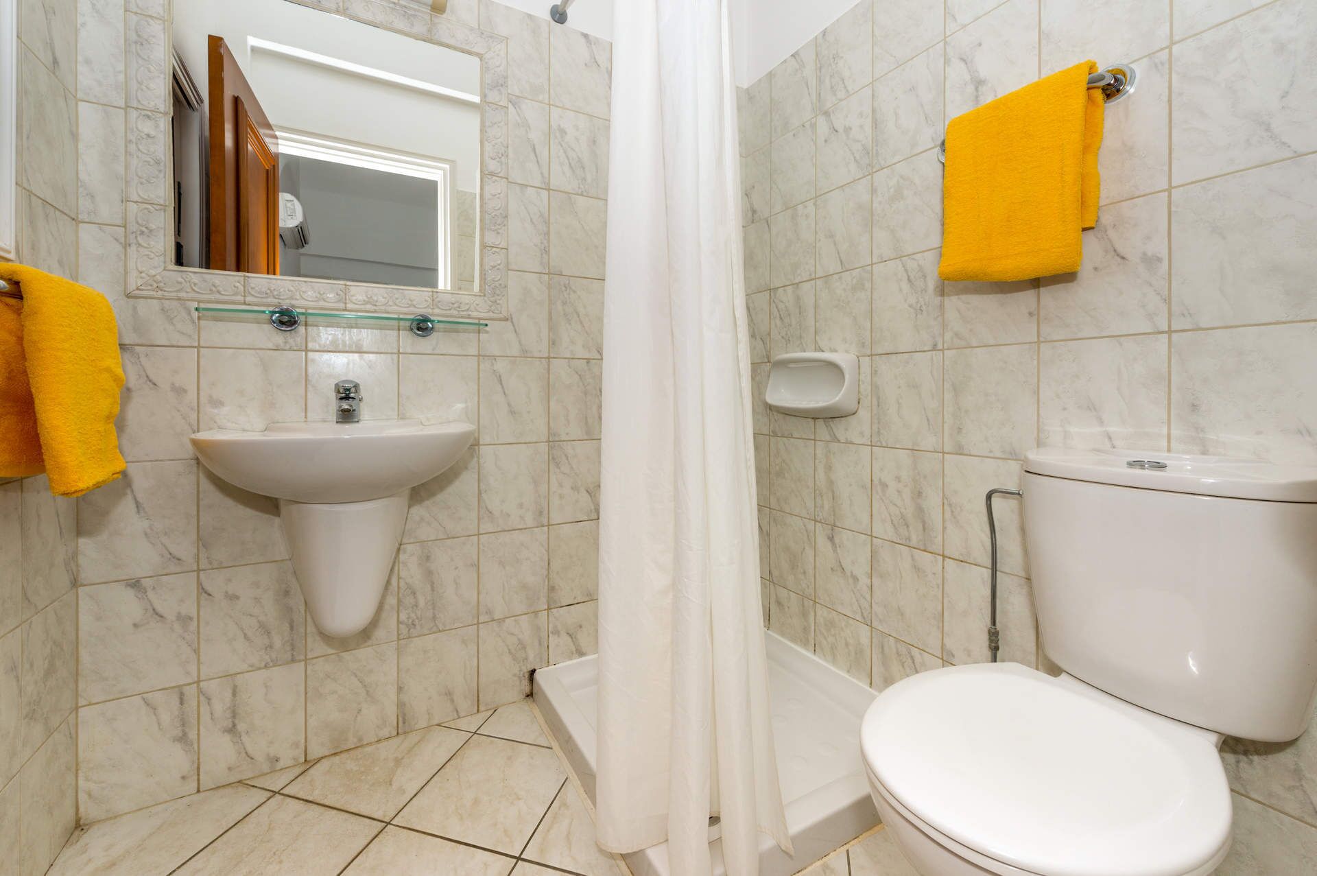 Une salle de bain avec un lavabo blanc, des toilettes et un rideau de douche.