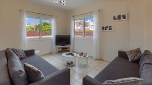 A living room with two grey sofas, a TV, and a coffee table. - Villa Semeli by Villa Plus (Peyia)